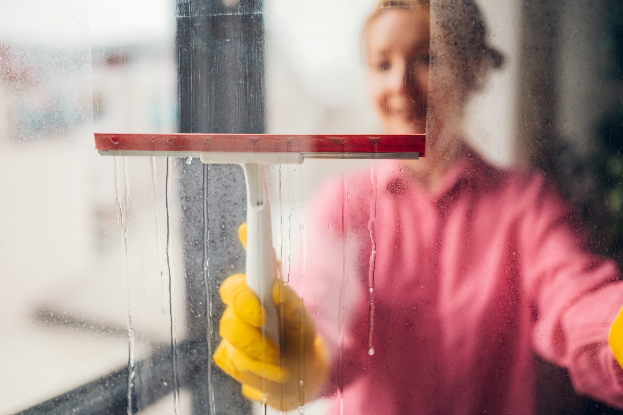 Smiling woman cleaning window with squeegee
